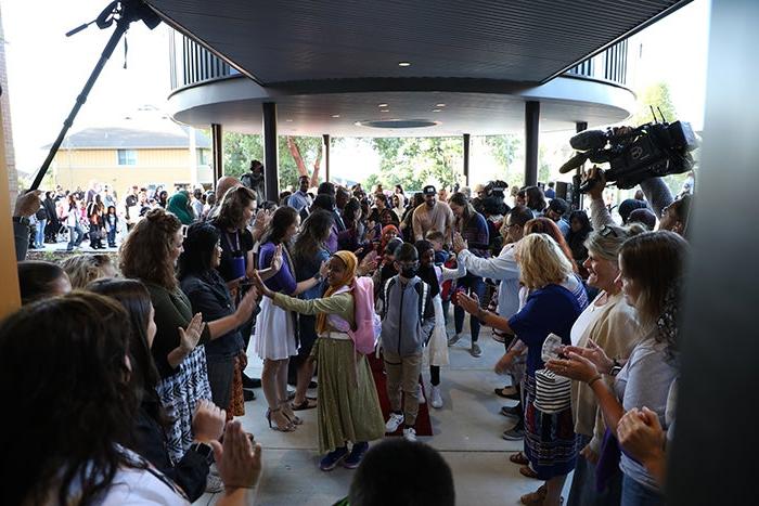 a crowd of people includes children and adults and are moving toward the camera